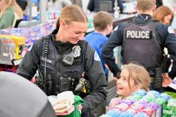 Ogden police department officer smiling at a young girl during a holiday shopping event in Utah.