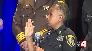 DJ Daniel raises his hand during a police swearing-in ceremony, wearing an honorary officer uniform.