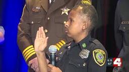 DJ Daniel raises his hand during a police swearing-in ceremony, wearing an honorary officer uniform.