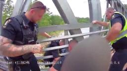 Bodycam view of Independence Police officers leaning over a bridge railing to pull a person to safety over the Cuyahoga River.