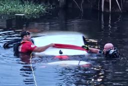 Emergency responders in water holding onto a submerged white vehicle during a rescue operation in Clearwater, Florida.