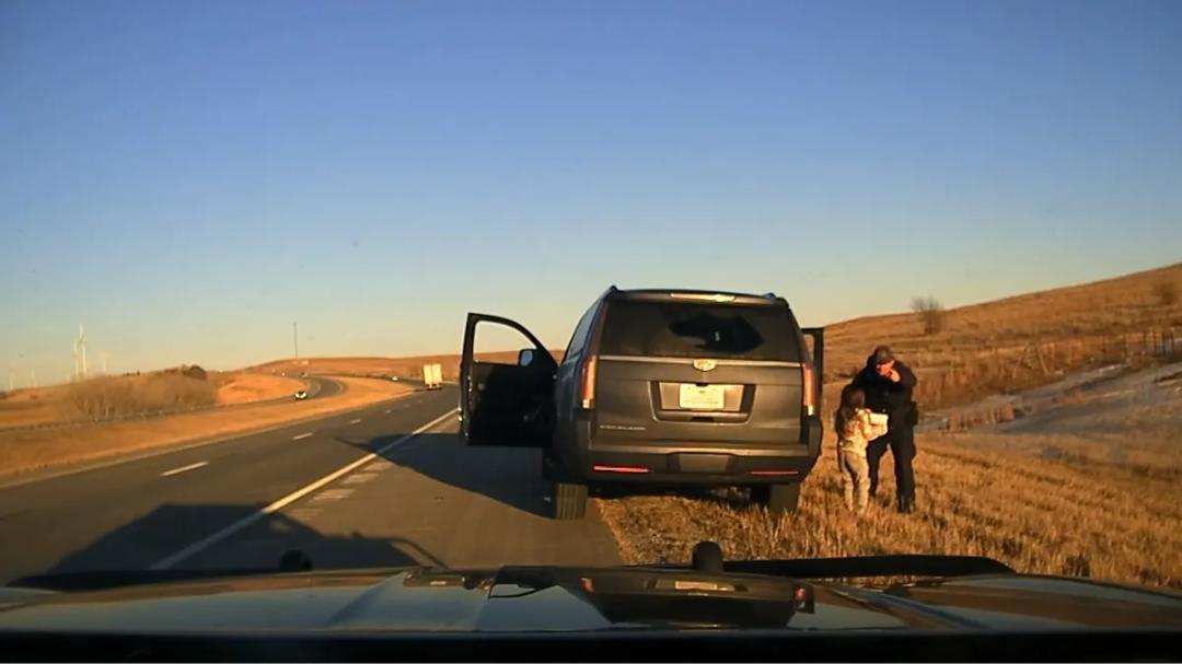 Image from the Kansas Highway Patrol showing the moment of a roadside rescue involving a trooper and a young kidnapping victim.