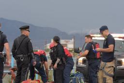 New Mexico State Police officers and Albuquerque Fire Rescue crews standing along a blue railing at a flood channel in Albuquerque, NM.