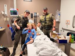 Michigan DNR officers Cullen and Wright visit rescued family members in a hospital room.