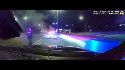 Police officer walking toward a car engulfed in flames on Interstate 88 in Oak Brook, Illinois.