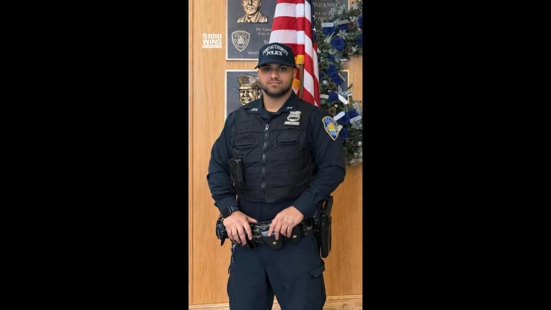 Port Authority Police Officer Elijah Ali standing in uniform next to an American flag.