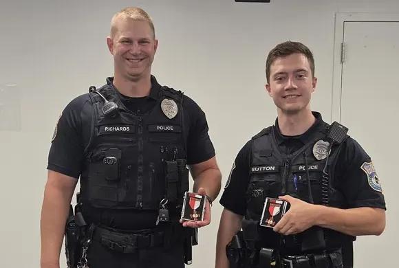 Officer Kevin Richards and Officer Tyler Sutton stand in uniform displaying their department commendations.