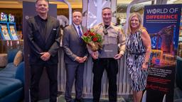 Officer Michael Monteleone holds a bouquet and an award while standing with LVMPD Foundation members