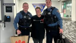 Officer Matt Tucker and Officer Dante Moore smile with a driver inside the Washington Township Police Department.