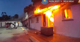 Body camera image of flames coming from the roof and doorway of a building at the Sarasota, Florida motel fire