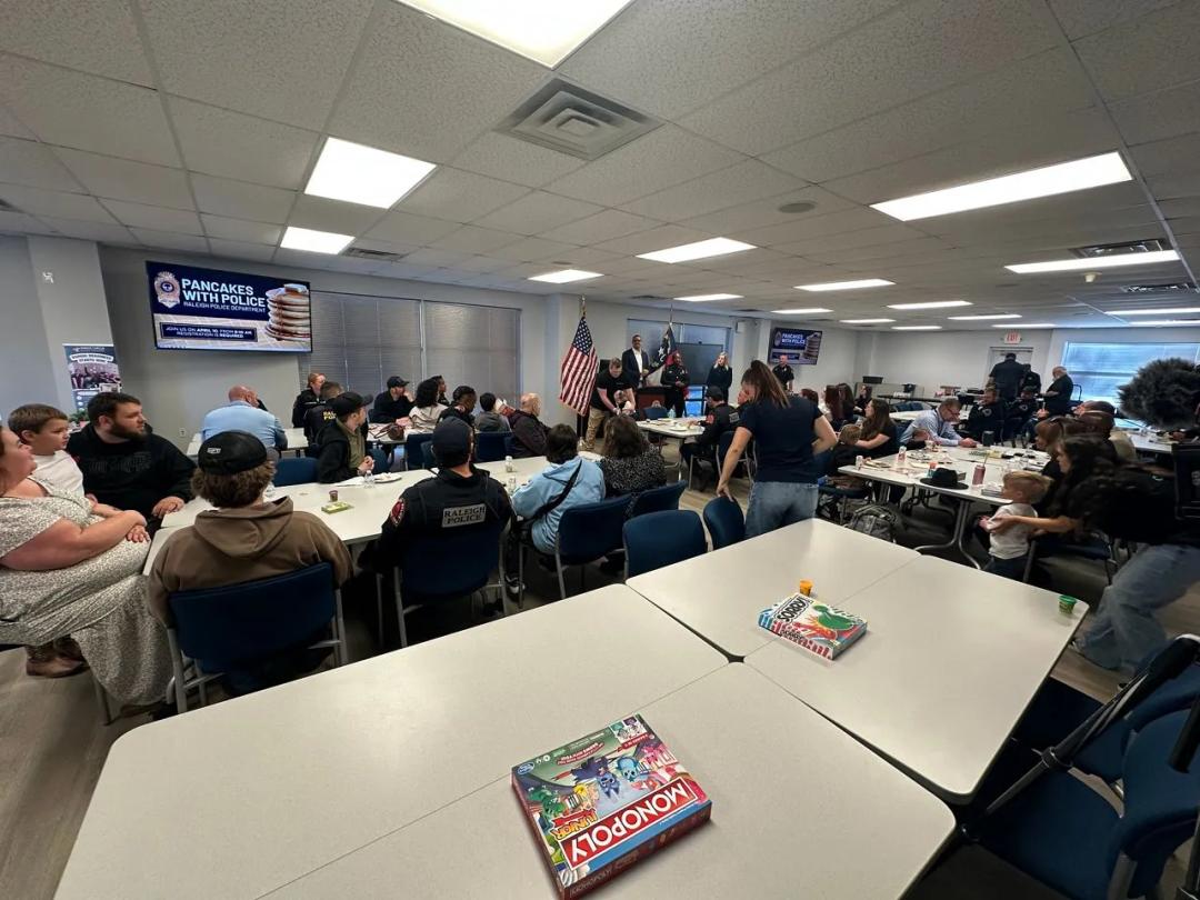 Raleigh Police Department officers and community members sitting at tables during a Pancakes with Police event