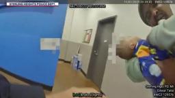 A relieved police officer holding a baby in a blue patterned onesie inside a store.