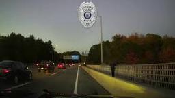 Dashcam view of Merrymeeting Bridge at twilight showing Officer Shirland standing near the railing during a rescue.