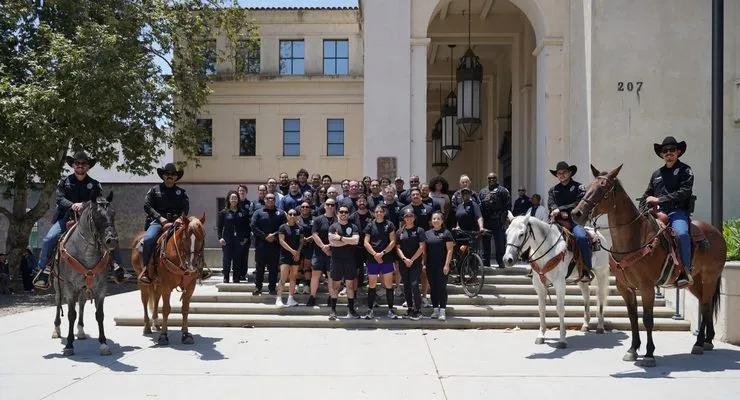 Pasadena California police officers and mounted unit members pose on steps with horses for the Special Olympics torch run.