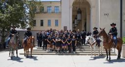 Pasadena California police officers and mounted unit members pose on steps with horses for the Special Olympics torch run.
