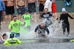 Forest Preserve District police officers and community members run into freezing water at a beach during a polar plunge.