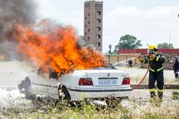 A white sedan engulfed in orange flames with a first responder working nearby in Florida.
