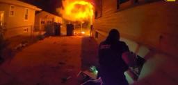 Body-worn camera view of an Omaha police officer working to pull a child from a basement window during a fire.