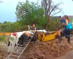 The scene of the police water rescue in Grant County, showing a backhoe stabilizing a truck as an officer saves a family.