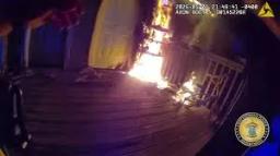 Bodycam footage screenshot showing a Chattanooga police officer approaching a Hixson apartment porch with large visible flames by the door.