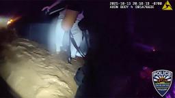 An Apache Junction police officer in the dark, rushing floodwater helps a man from his submerged vehicle during a night rescue.