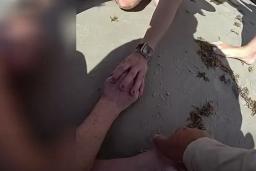 Close-up of hands on the sand during a police rescue at New Smyrna Beach
