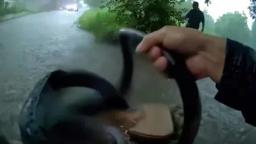 A first responder wades through high water next to a vehicle during a storm rescue.